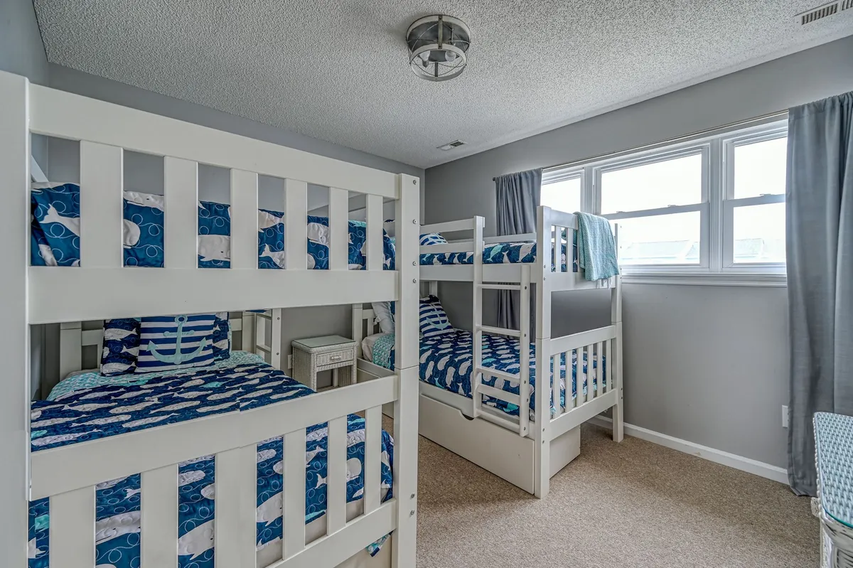 A cheerful and cozy interior image of the condo's bunkroom, featuring colorful bunk beds and bright windows. The space is designed with children in mind, creating an inviting retreat for kids after a long day outdoors.