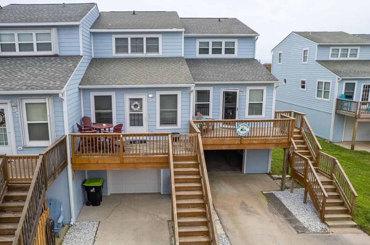 A spacious wooden deck with outdoor seating, ideal for relaxation or dining al fresco. The area feels open and connected to the outdoors, with a welcoming house number sign adding a personal touch.